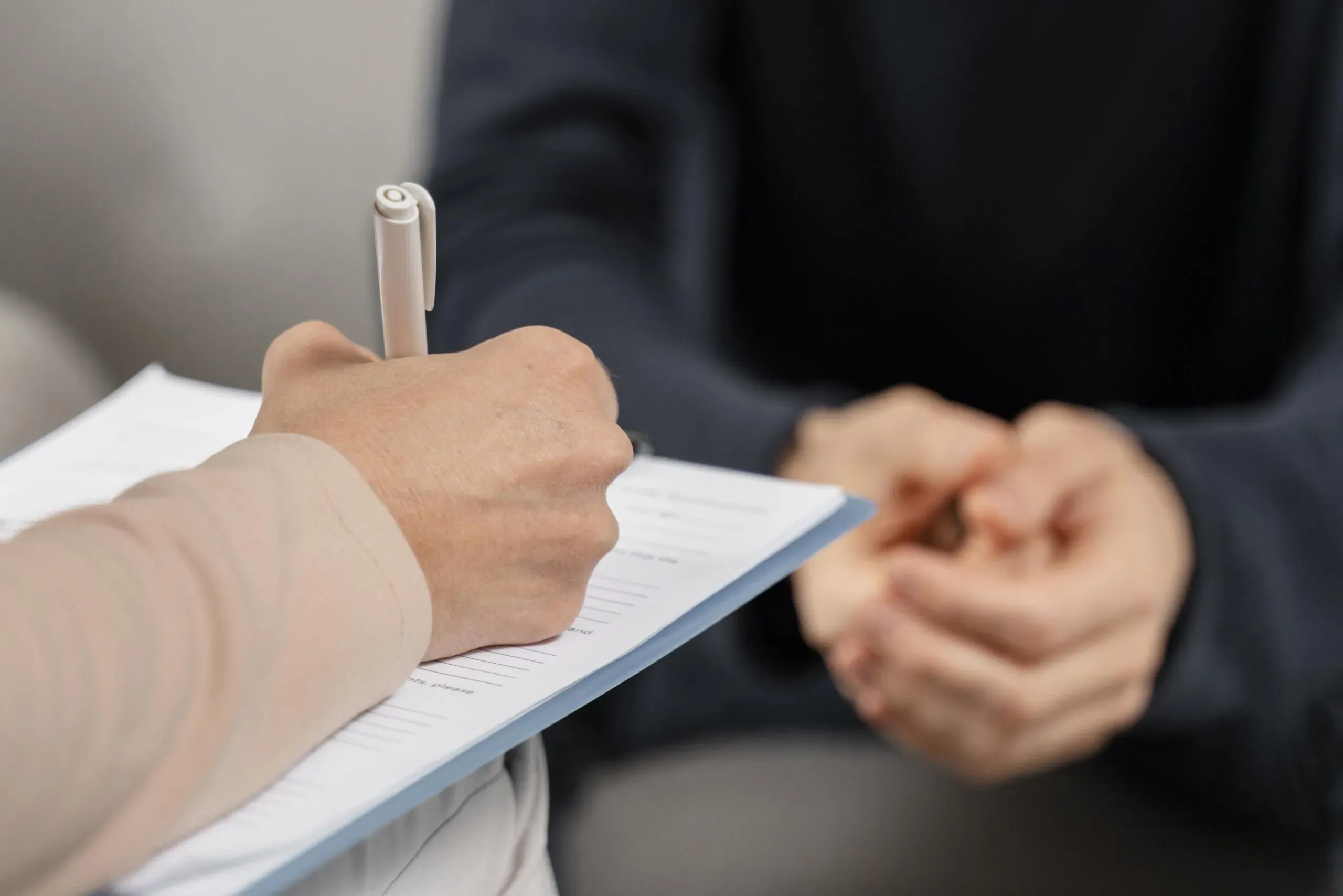 Mains d'une personne remplissant des documents administratifs pour l'accompagnement des familles.